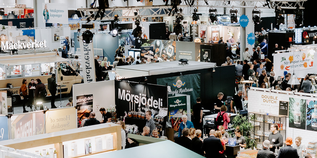 Produkter och tjänster 1 Mässa med utställare och besökare, montrar och skyltar fyller den livliga lokalen.